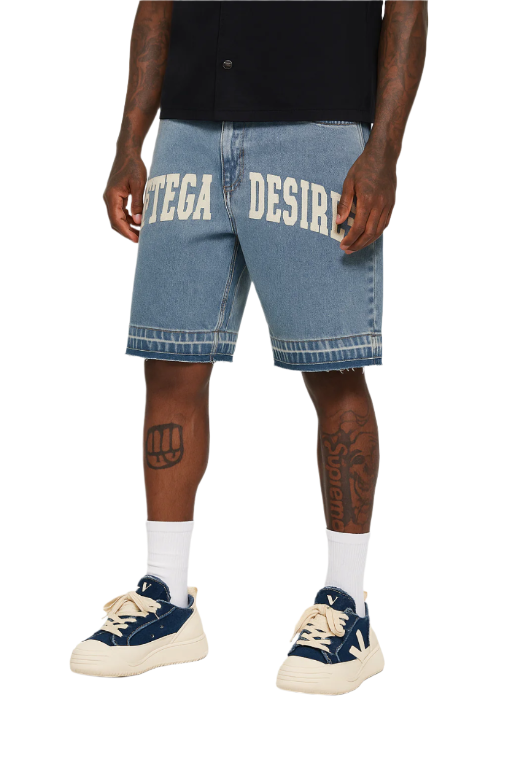 Person wearing blue denim shorts with 'DESIRES' printed on them, paired with navy sneakers and white socks.